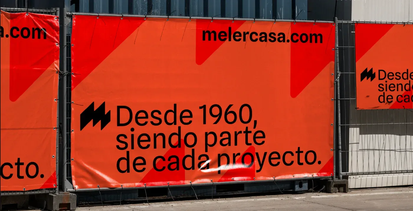 Lonas naranjas de vallado de obra con el claim Desde 1960, siendo parte de cada proyecto y la dirección melercasa.com.